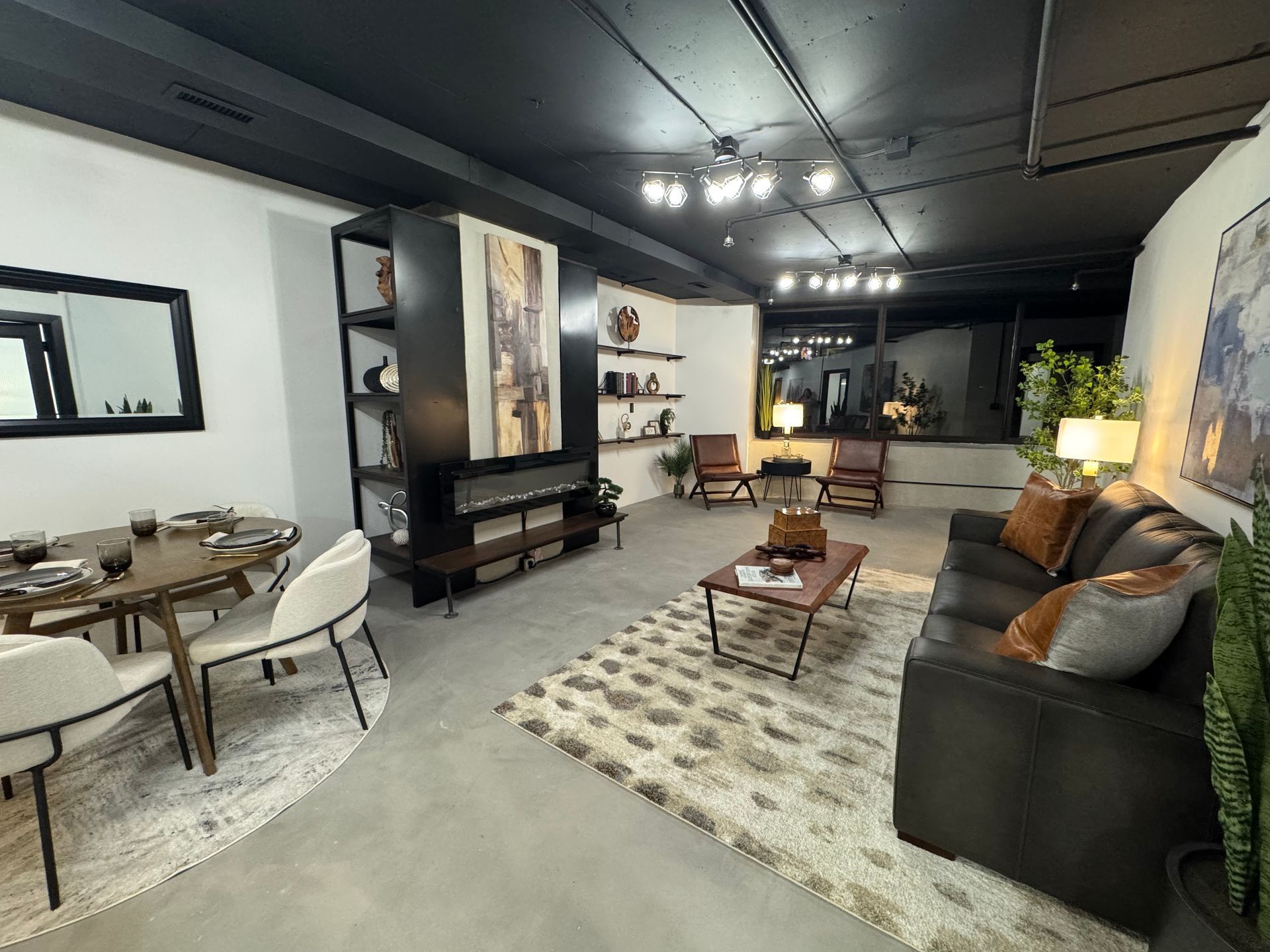Modern living room with dining area. Dark ceiling, gray floor. Black entertainment unit, brown sofa, area rug.