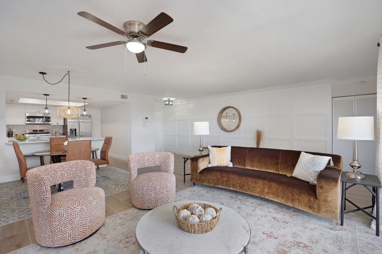 A living room with a couch , chairs , and a ceiling fan.