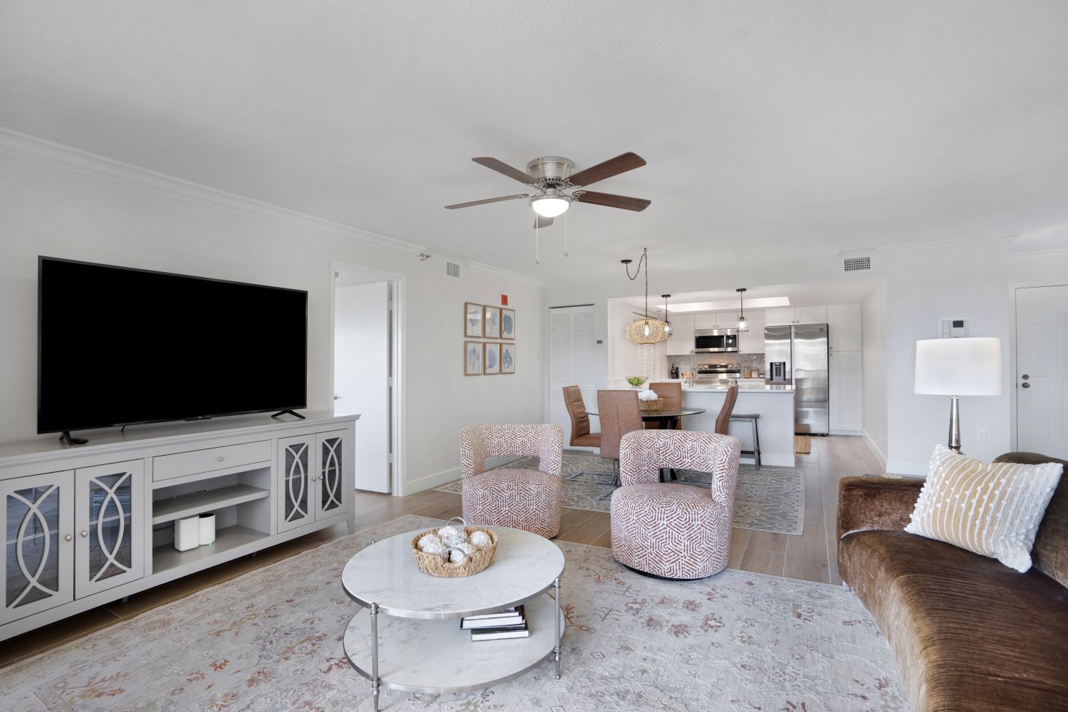 A living room with a couch , chairs , and a flat screen tv.
