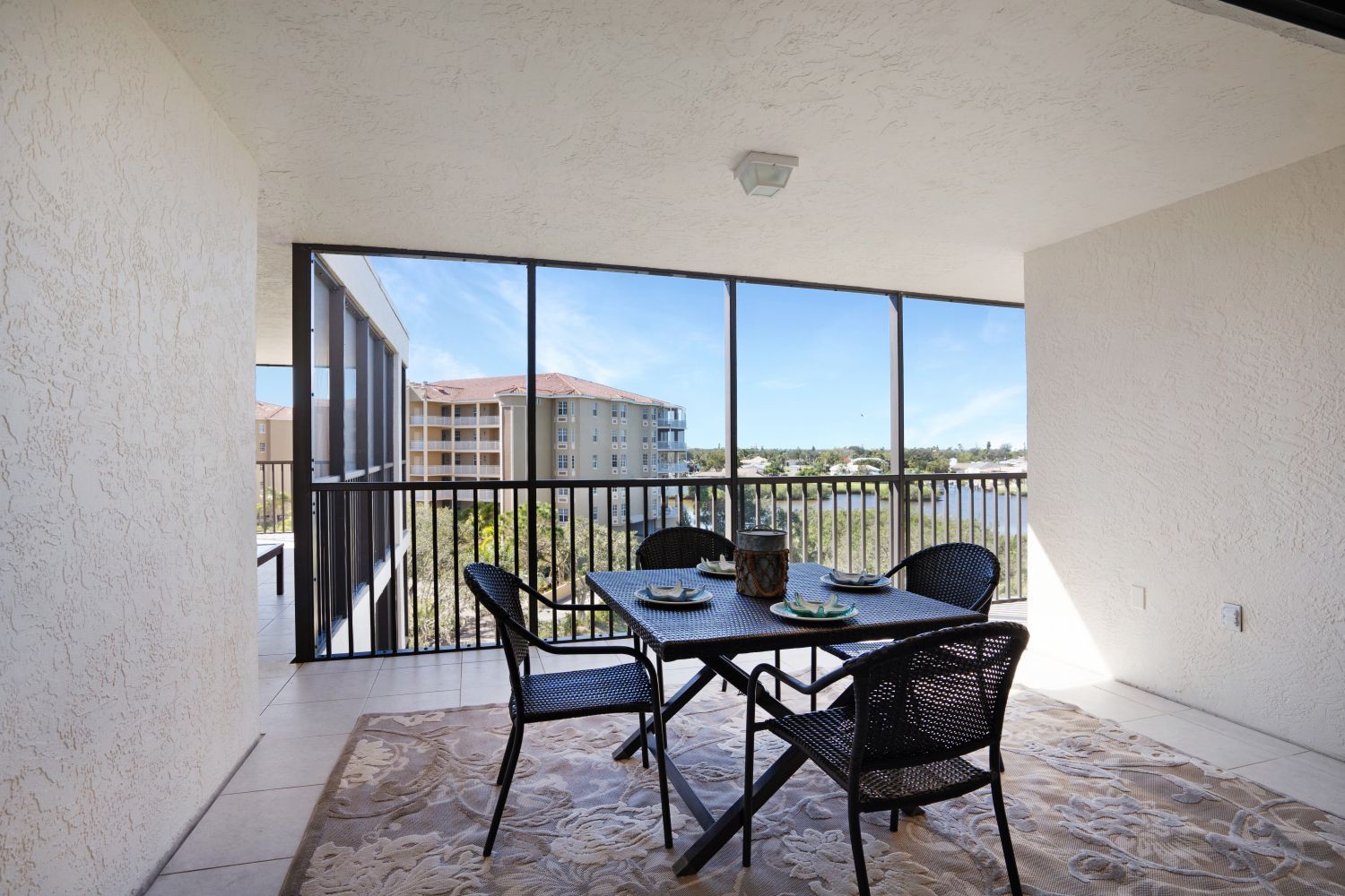 There is a table and chairs on the balcony with a view of the city.