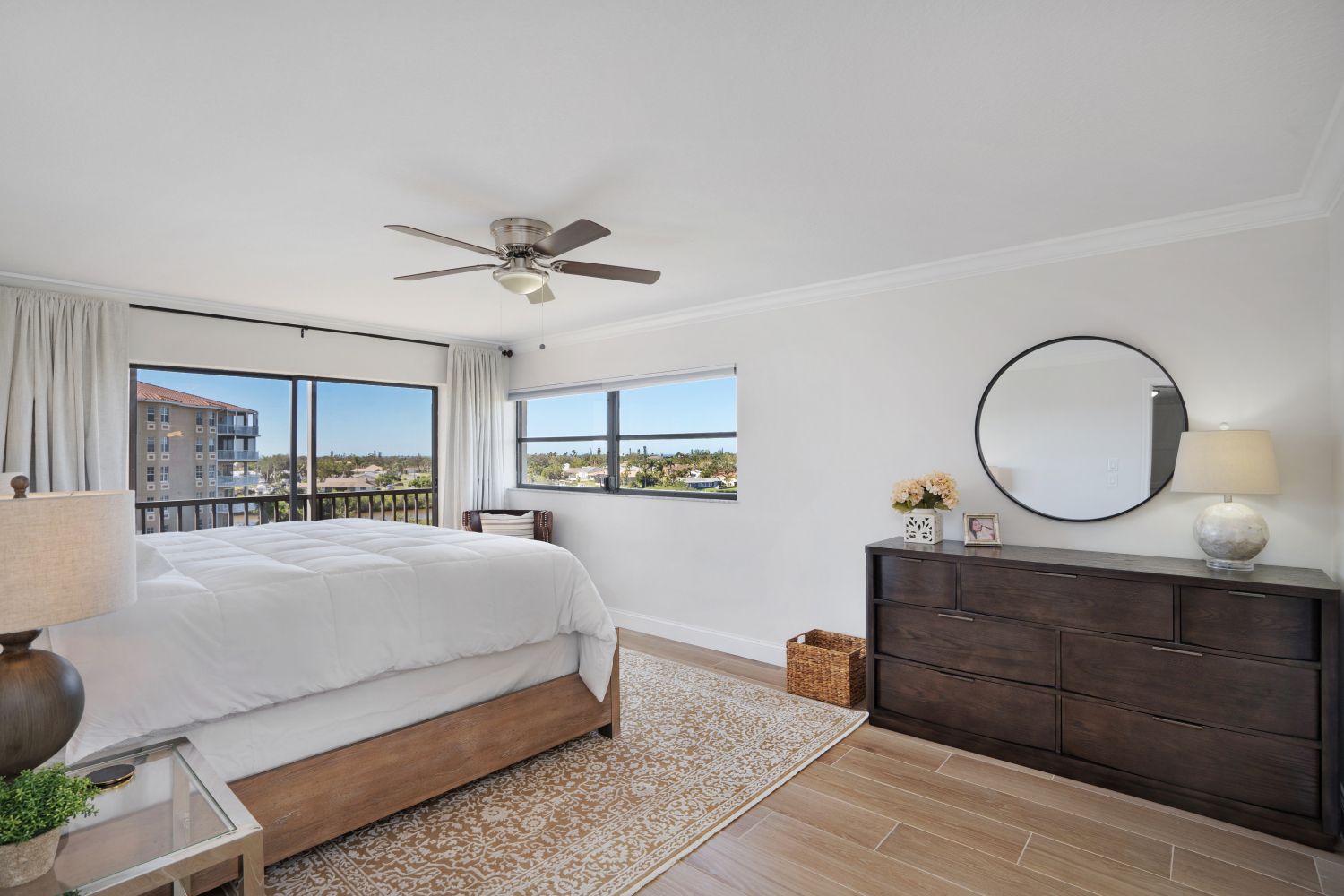 A bedroom with a bed , dresser , mirror and ceiling fan.