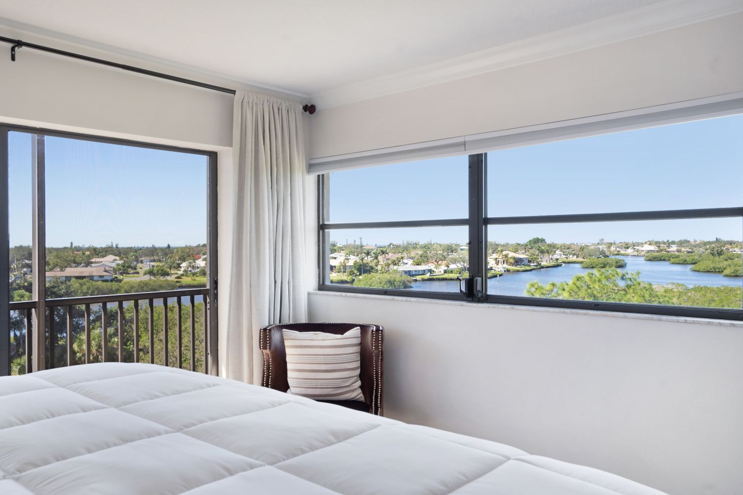 A bedroom with a bed and a chair and a view of a river.