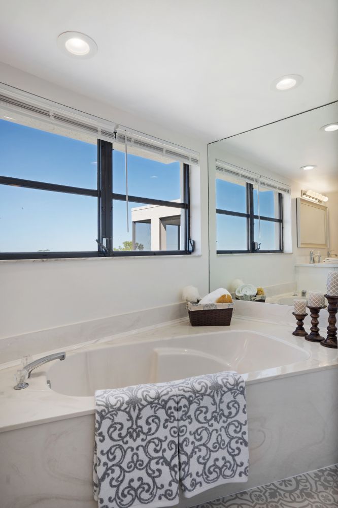 A bathroom with a large tub and a large mirror.