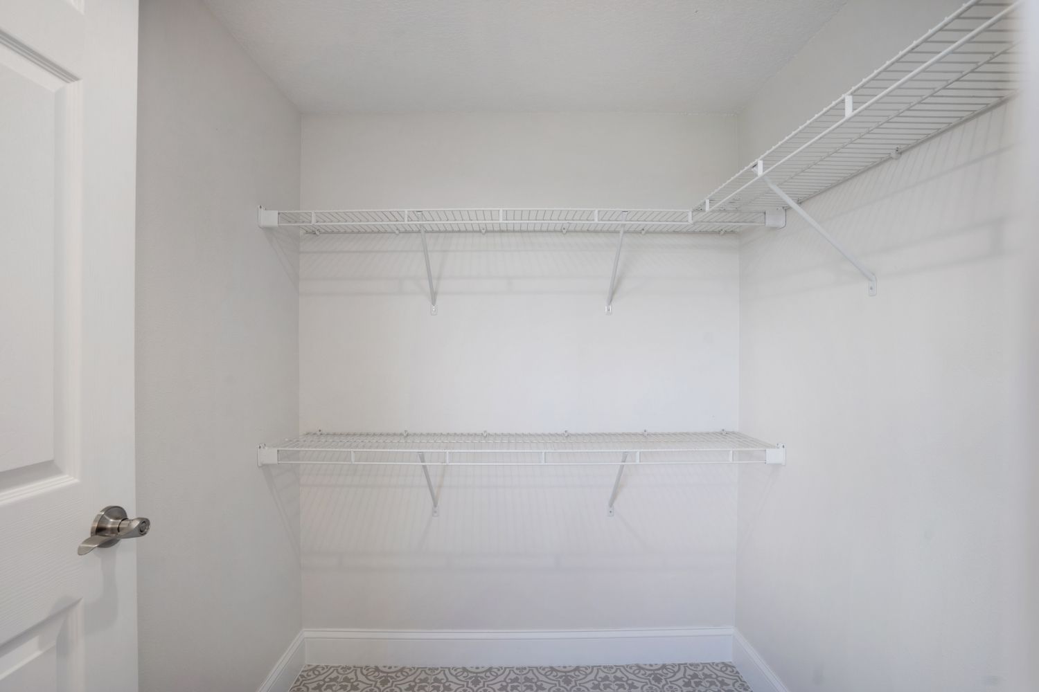 An empty walk in closet with shelves and a door.
