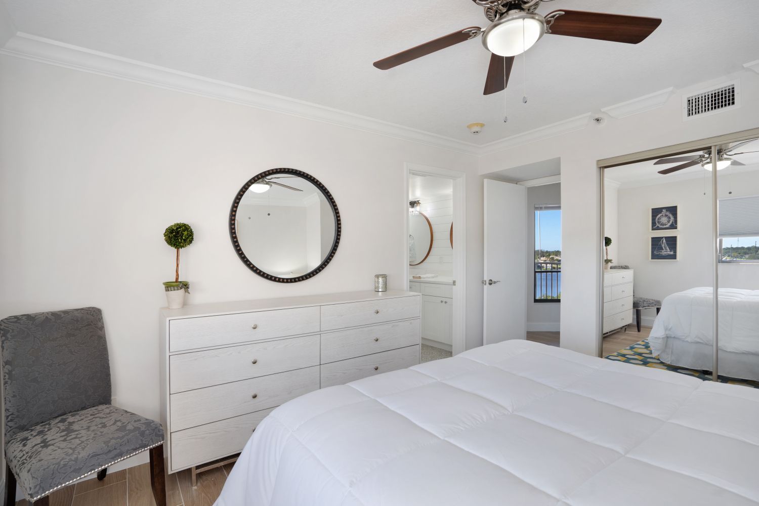 A bedroom with a bed , dresser , chair and ceiling fan