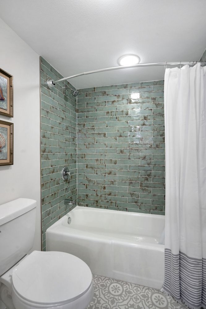 A bathroom with a toilet , tub and shower.