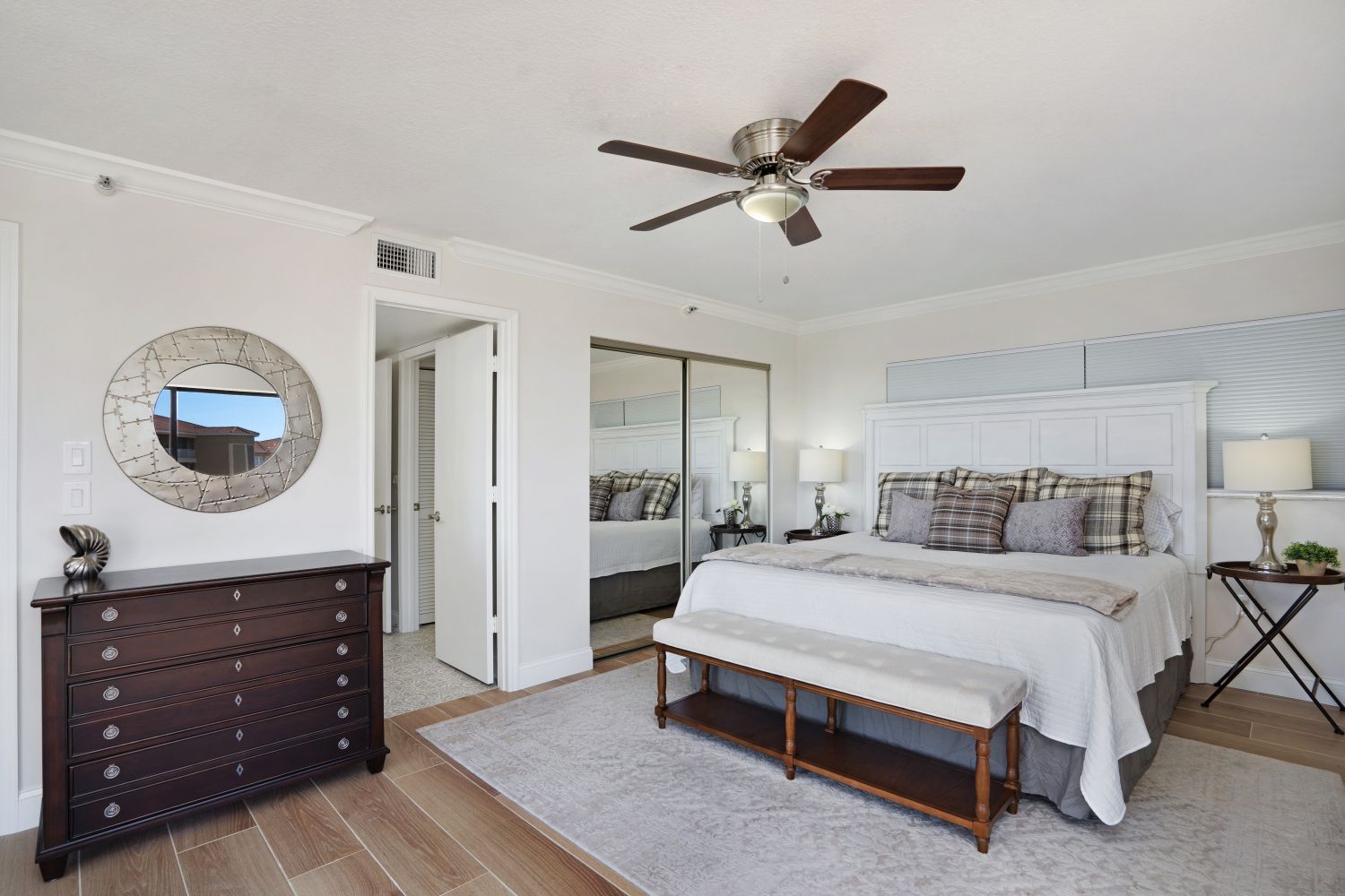 A bedroom with a bed , dresser , mirror and ceiling fan.