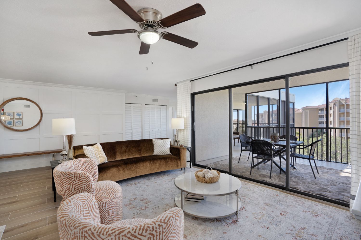 A living room with a couch , chairs , coffee table and ceiling fan.