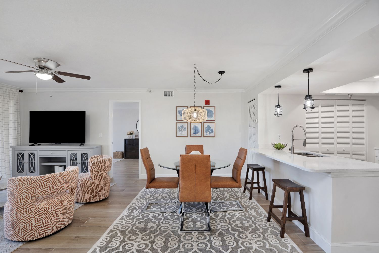 A living room with a dining room table and chairs and a flat screen tv.