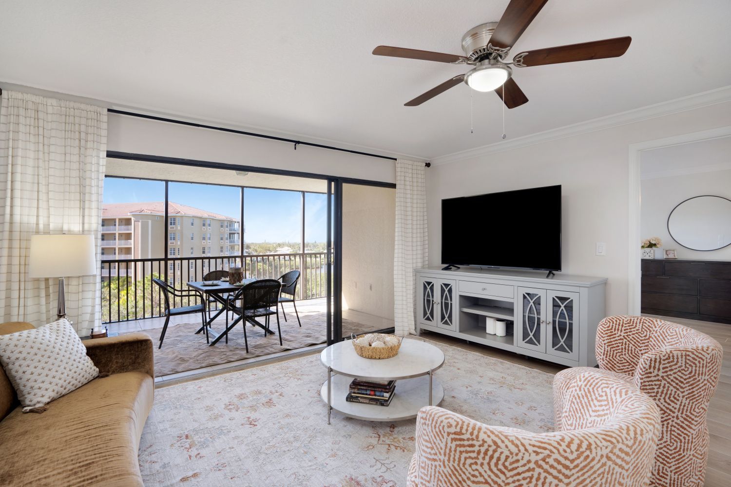 A living room with a ceiling fan and a flat screen tv