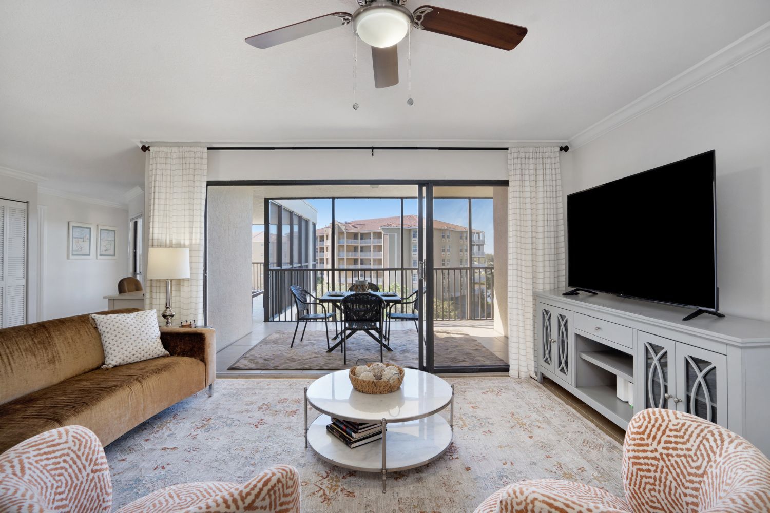 A living room with a couch , chairs , coffee table and television.