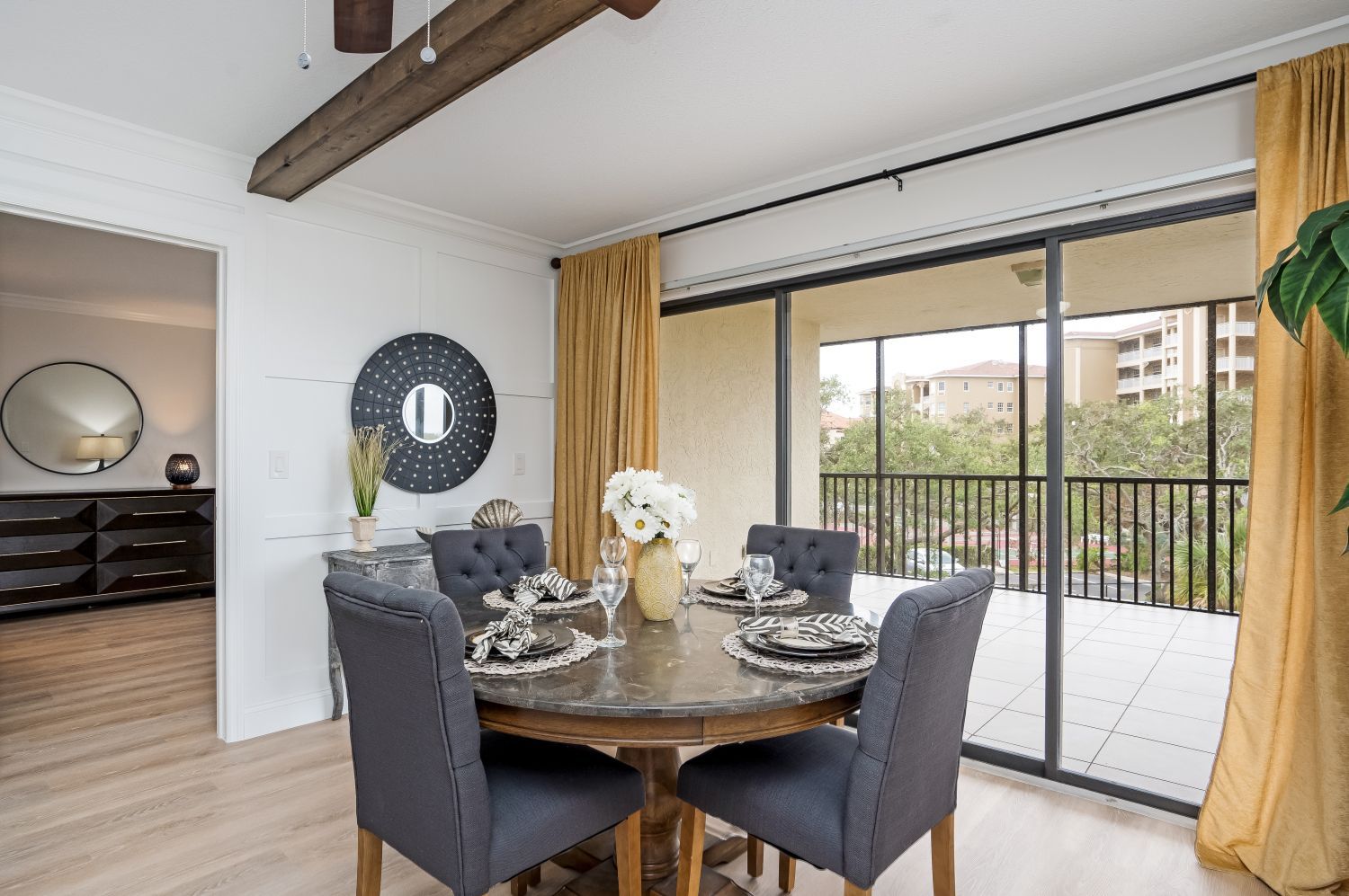 A dining room with a table and chairs and a balcony.