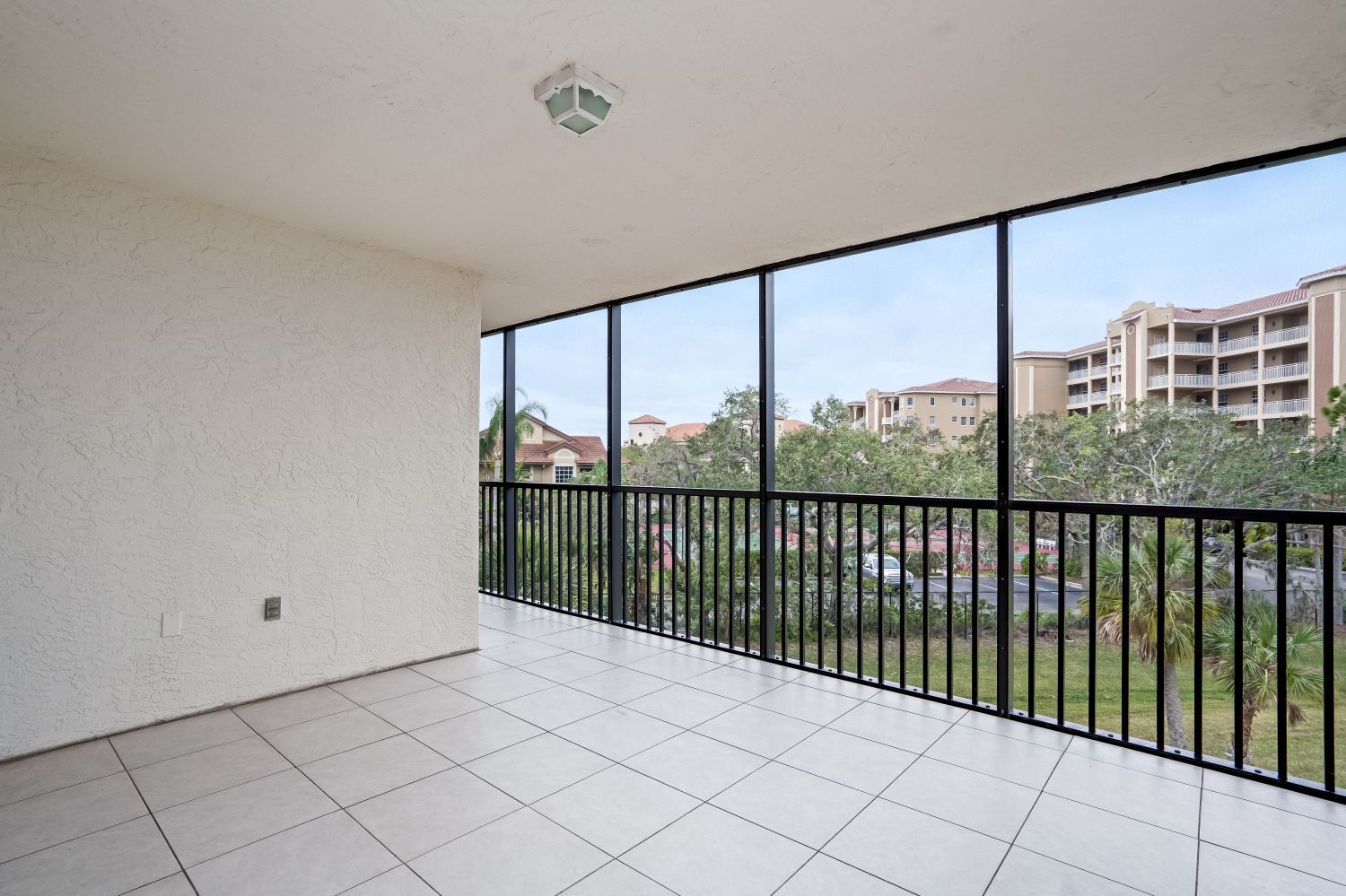 An empty balcony with a screened in view of a city