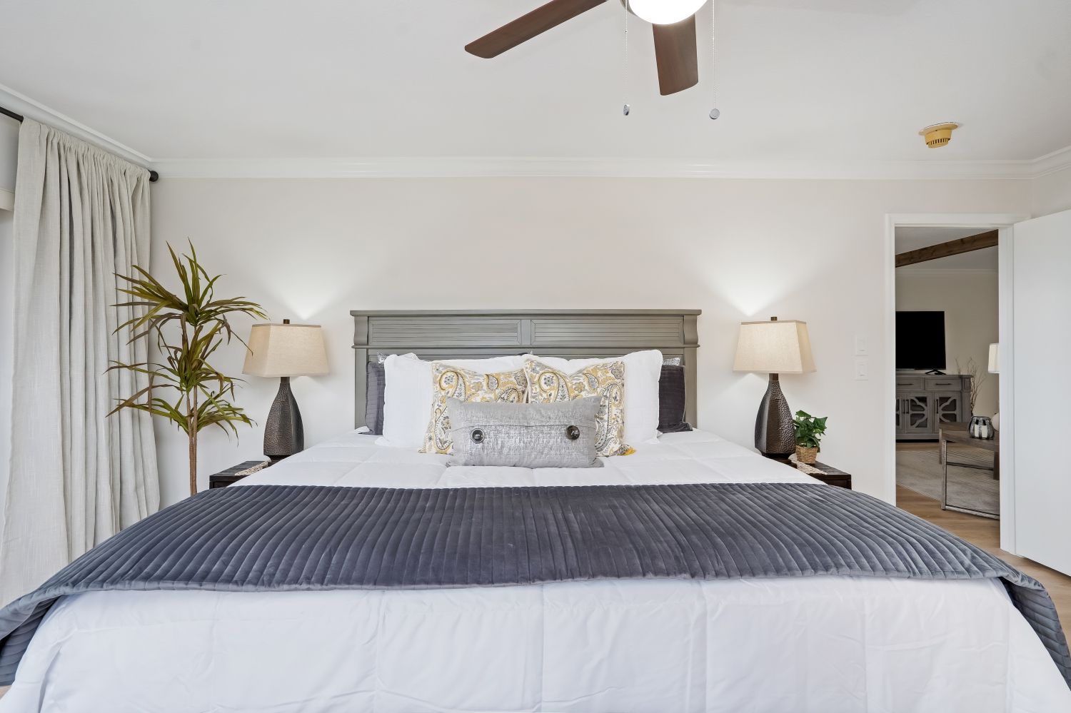 A bedroom with a king size bed and a ceiling fan.