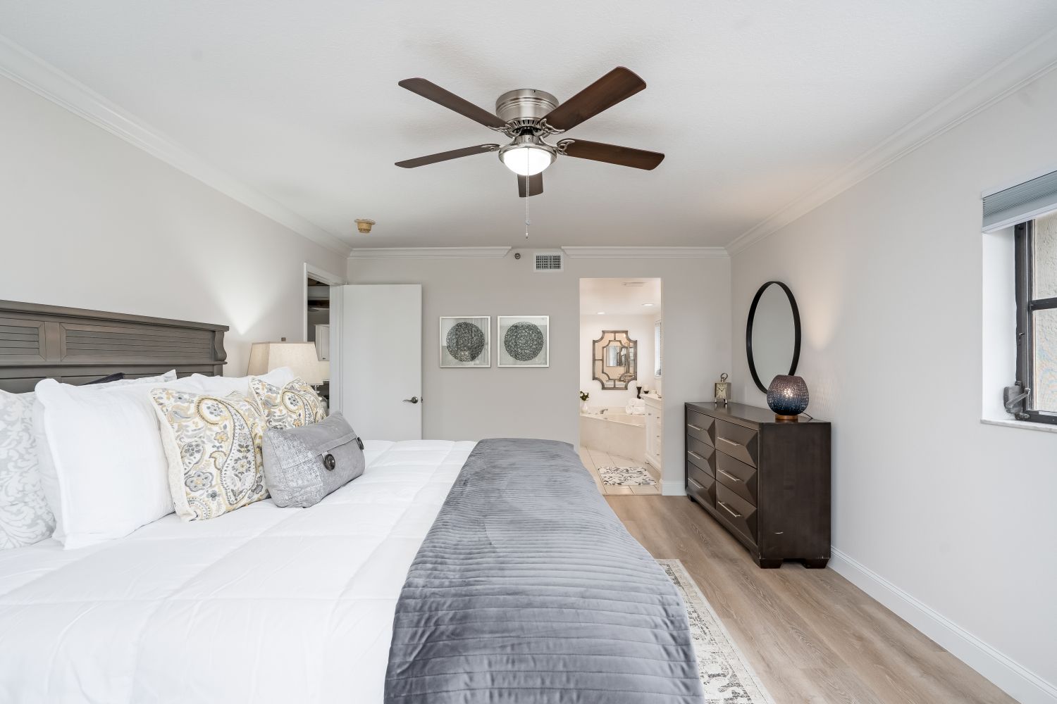 A bedroom with a bed , dresser , and ceiling fan.
