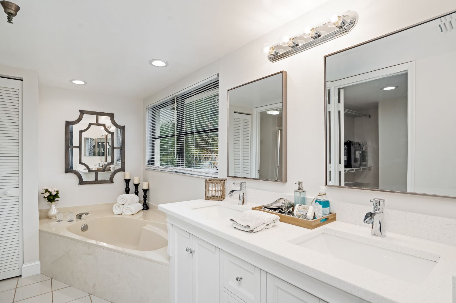 A bathroom with two sinks , a tub and two mirrors.