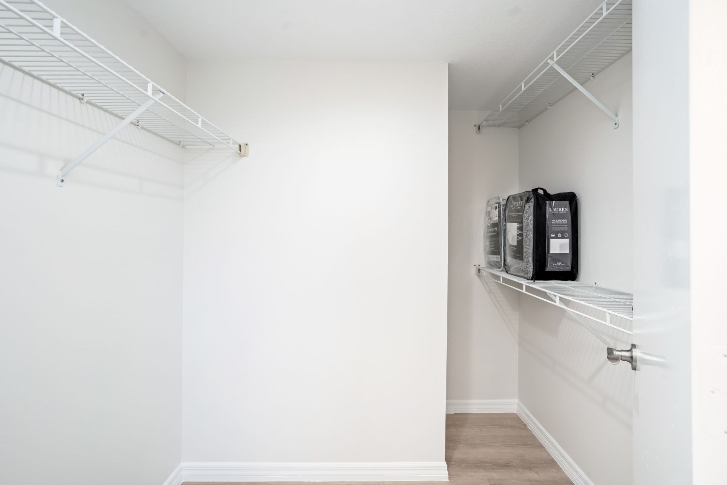 A walk in closet with lots of shelves and a door.
