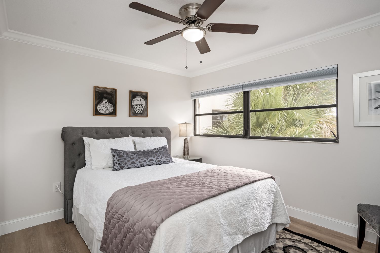 A bedroom with a bed , ceiling fan , and window.