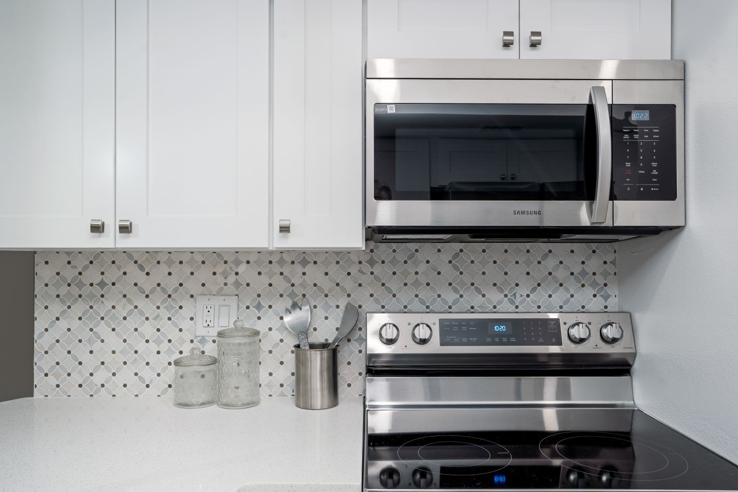A kitchen with a stove , microwave , and white cabinets.