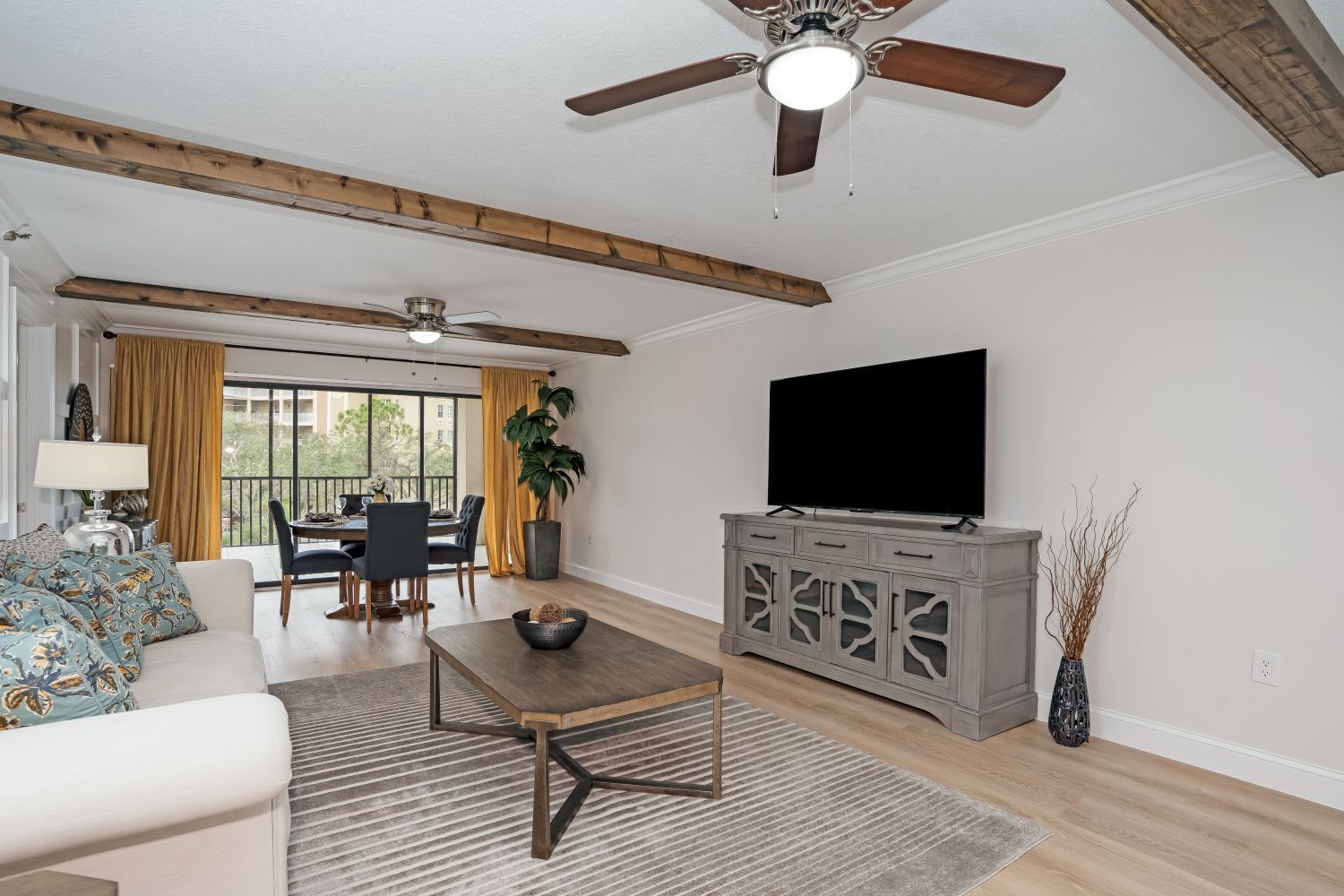 A living room with a ceiling fan and a flat screen tv.