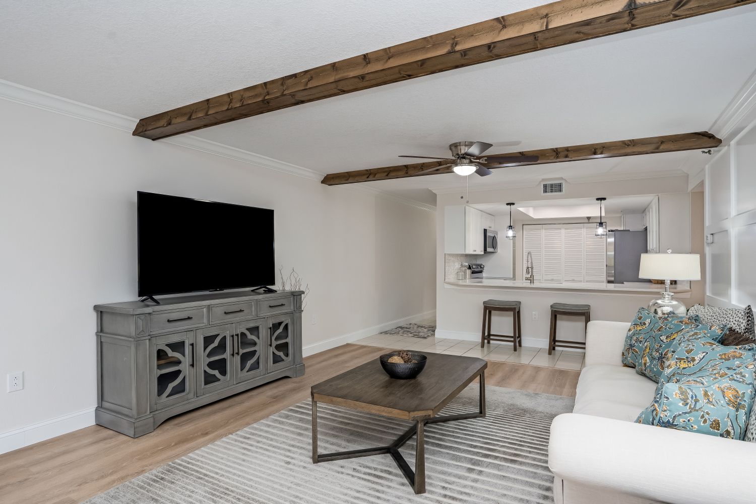 A living room with a couch , coffee table , television and wooden beams.