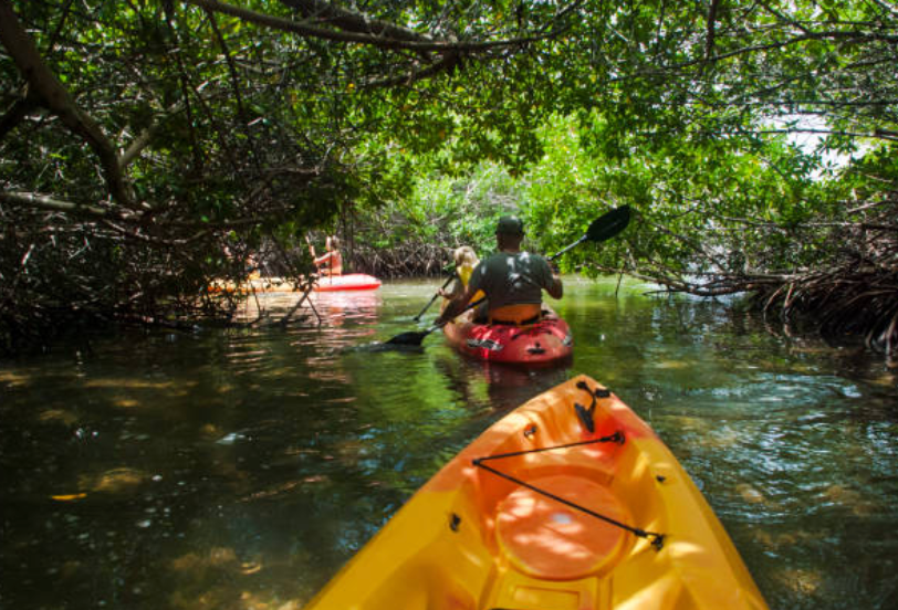 A man is paddling a yellow kayak on a river.