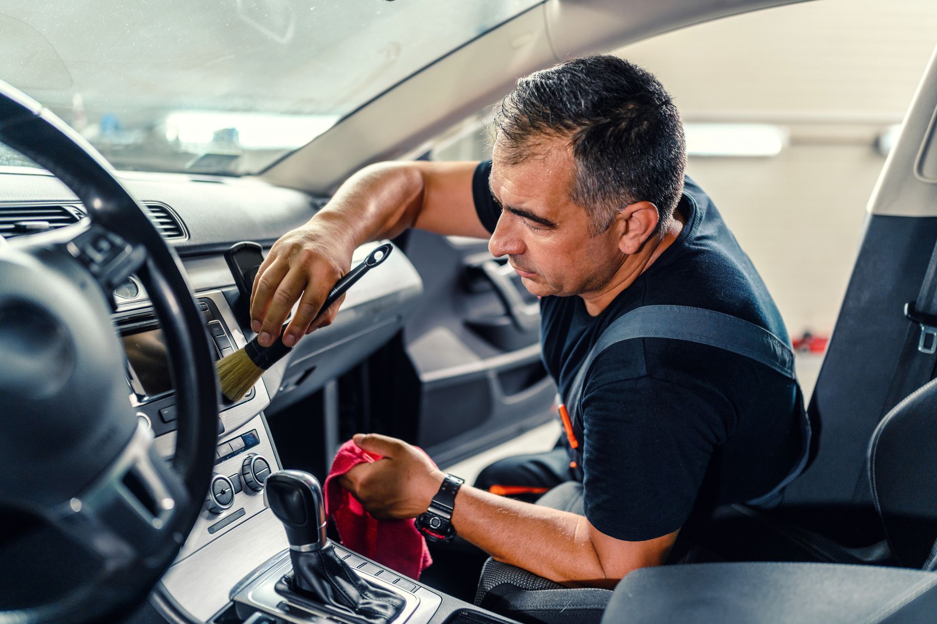 A person is cleaning the hood of a car with a cloth.
