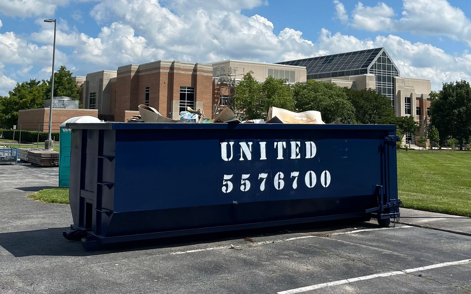 Large blue Local dumpster rental company container on a construction site with wood framing. Large blue Local dumpster rental company container on a construction site with wood framing.