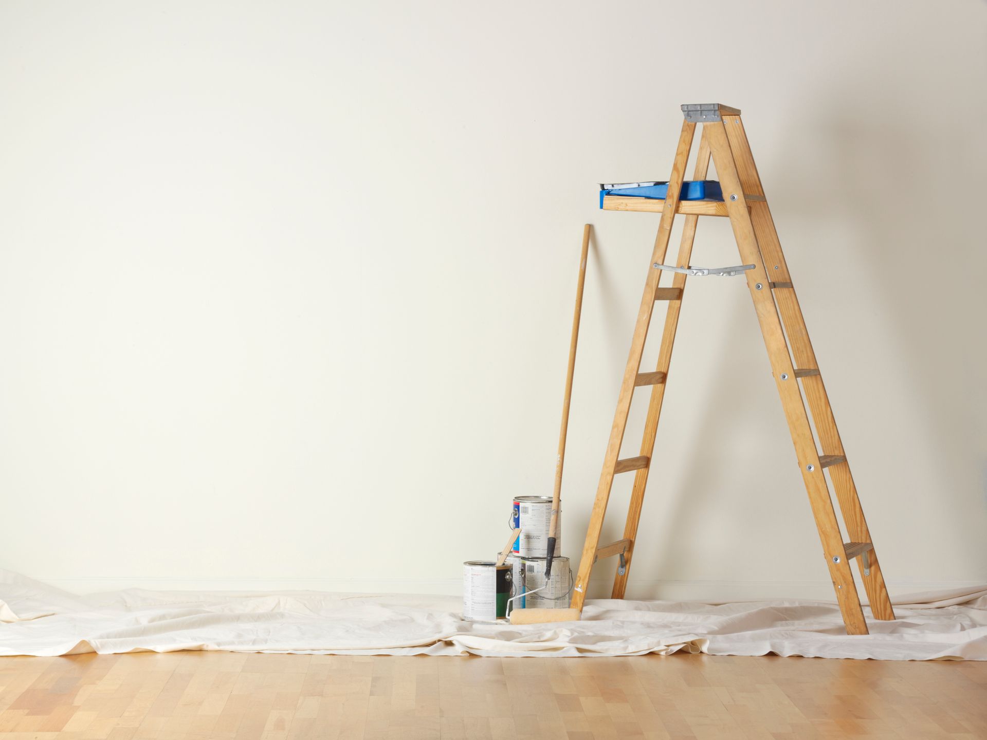 A wooden ladder is leaning against a wall next to paint cans.