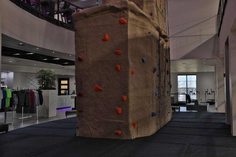 Indoor climbing wall with colorful holds. Retail area in the background.