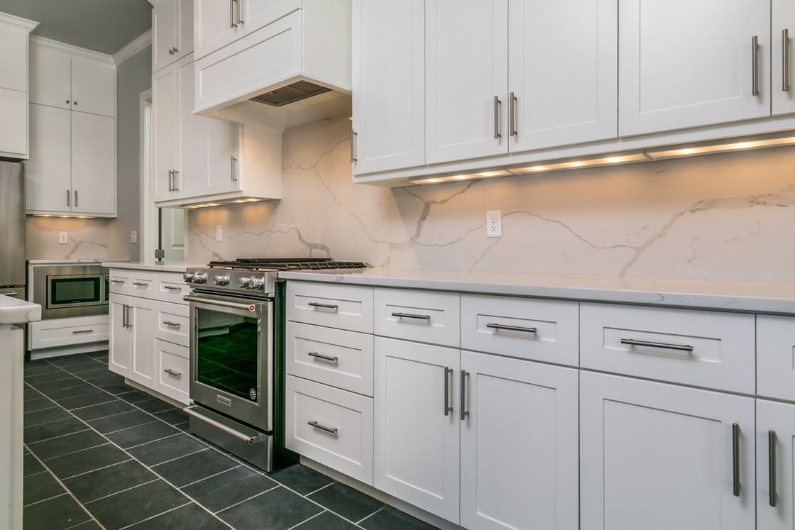 White kitchen with cabinets, stainless steel appliances, and gray countertops.