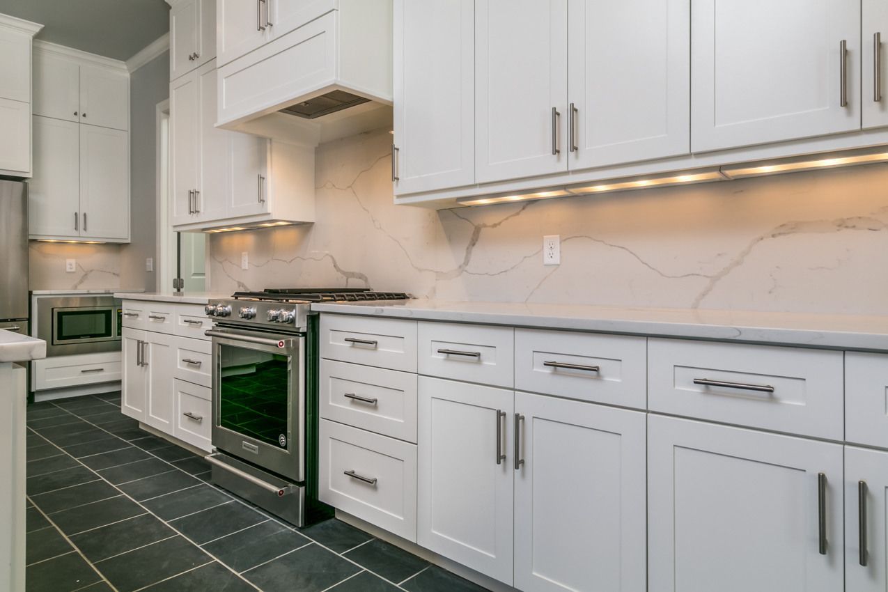 White kitchen with cabinets, stainless steel appliances, and gray countertops.