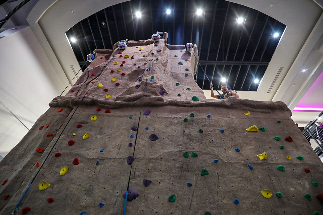 Rock climbing wall with colorful holds; people climbing indoors.