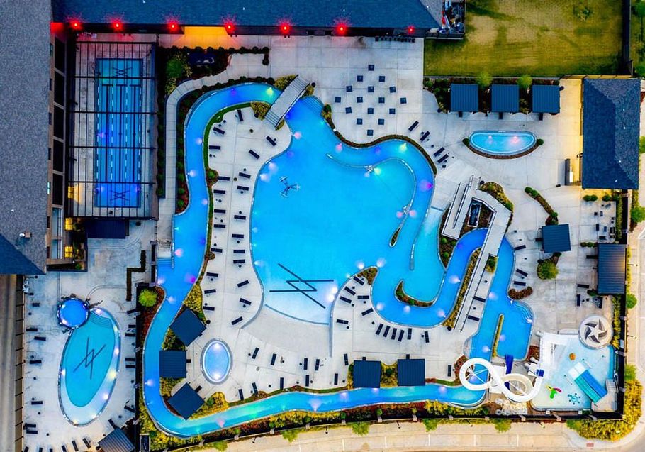 Aerial view of a brightly lit water park with pools, slides, and lounging areas.