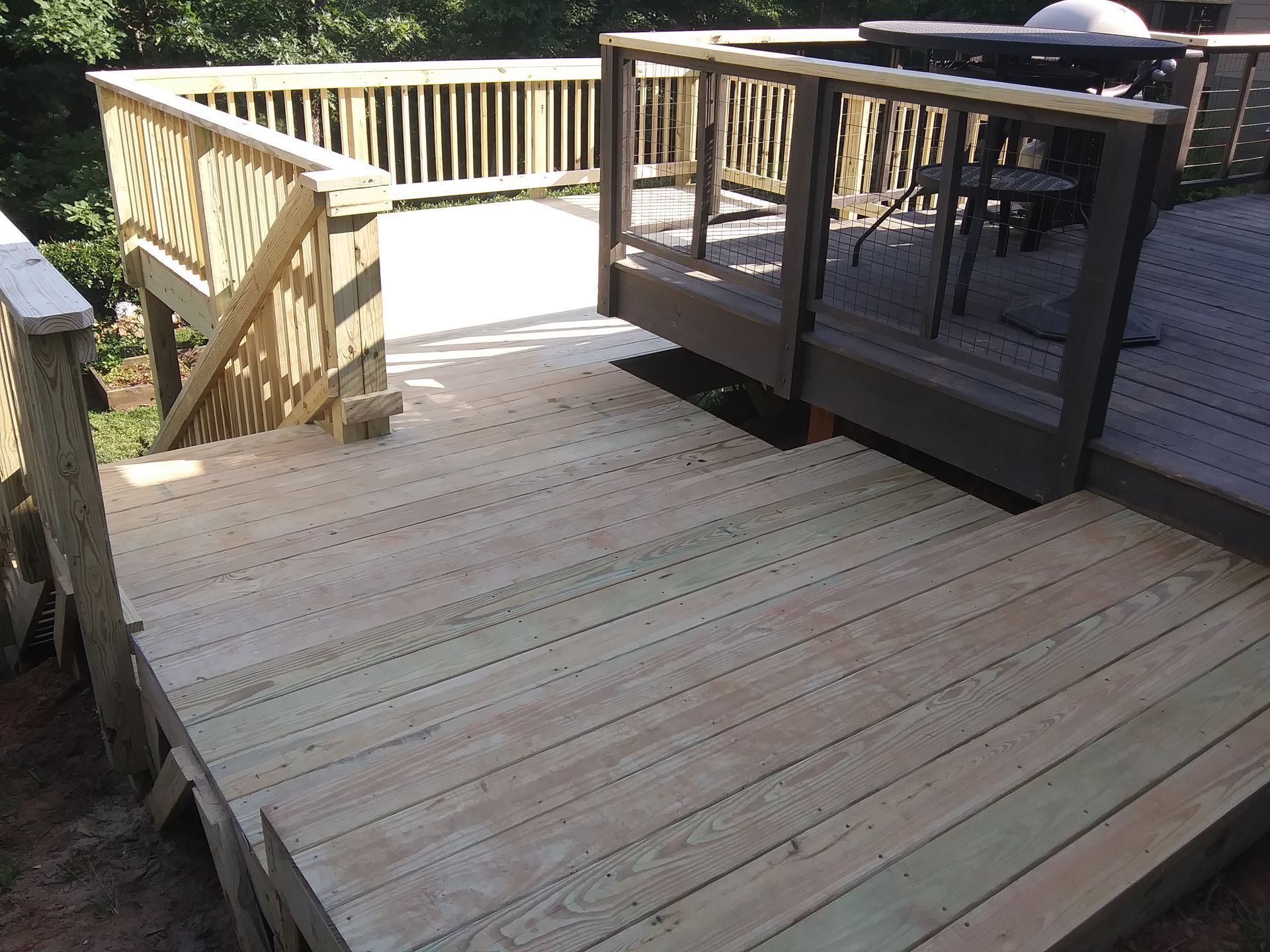 Wooden deck with multiple levels and railings outdoors.
