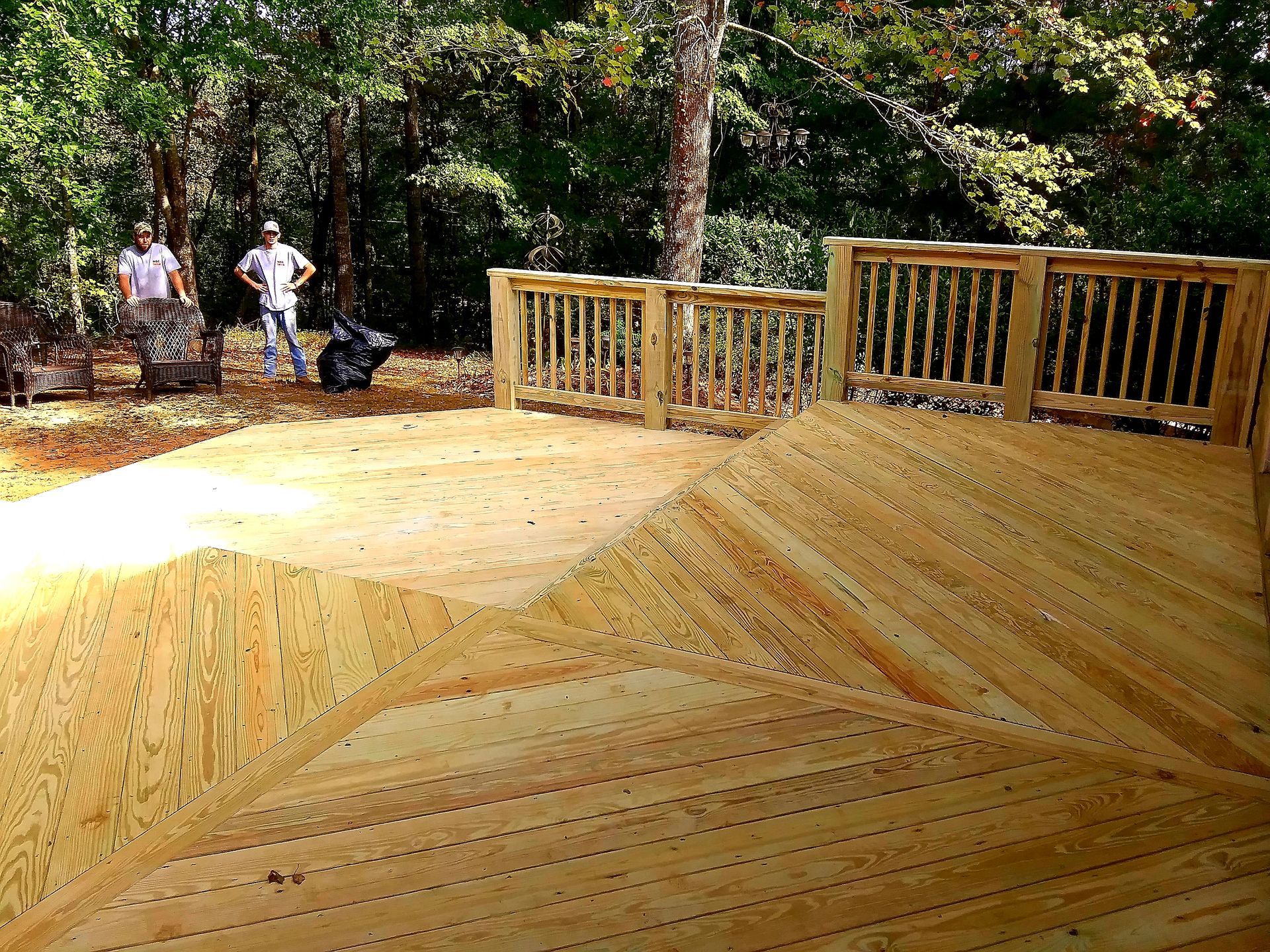 New wooden deck with railings, men standing in the background. Sunny outdoor setting.
