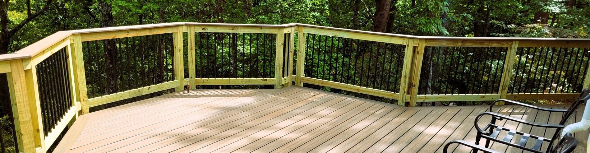 Wooden deck with railings overlooking a green forest.
