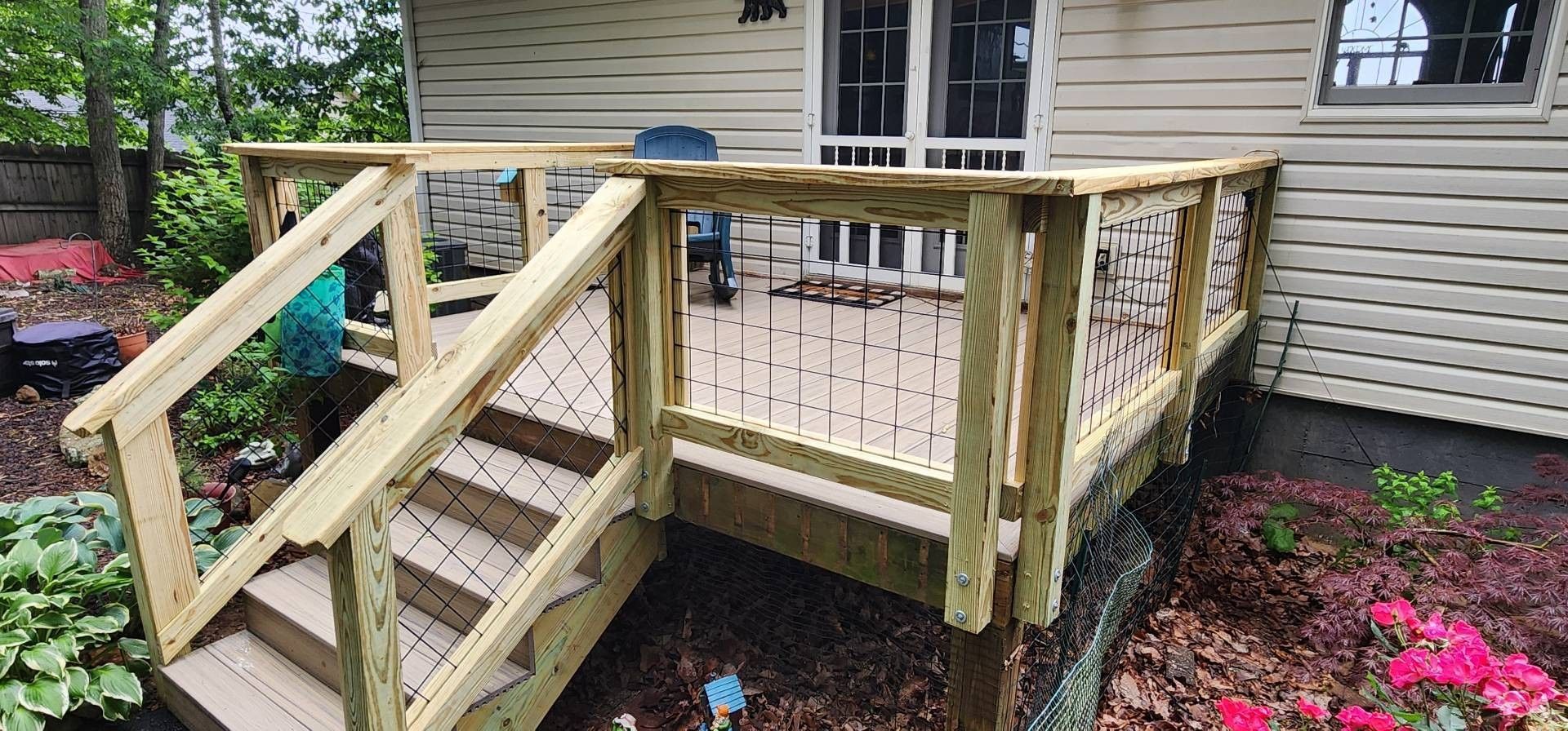 Wooden deck with stairs, cable railings, and a view of a house.