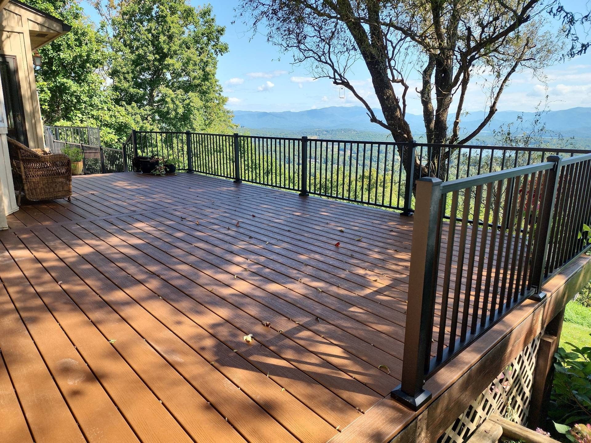 Wooden deck with black railing overlooking a mountain view.