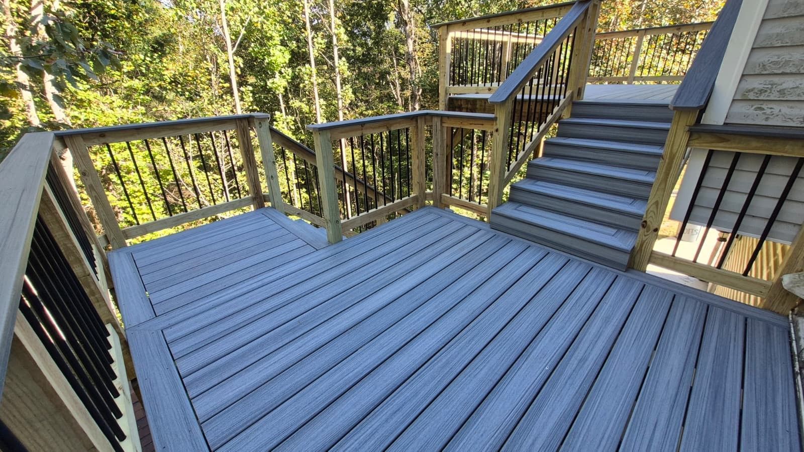 Wooden deck with stairs, surrounded by railings and trees.