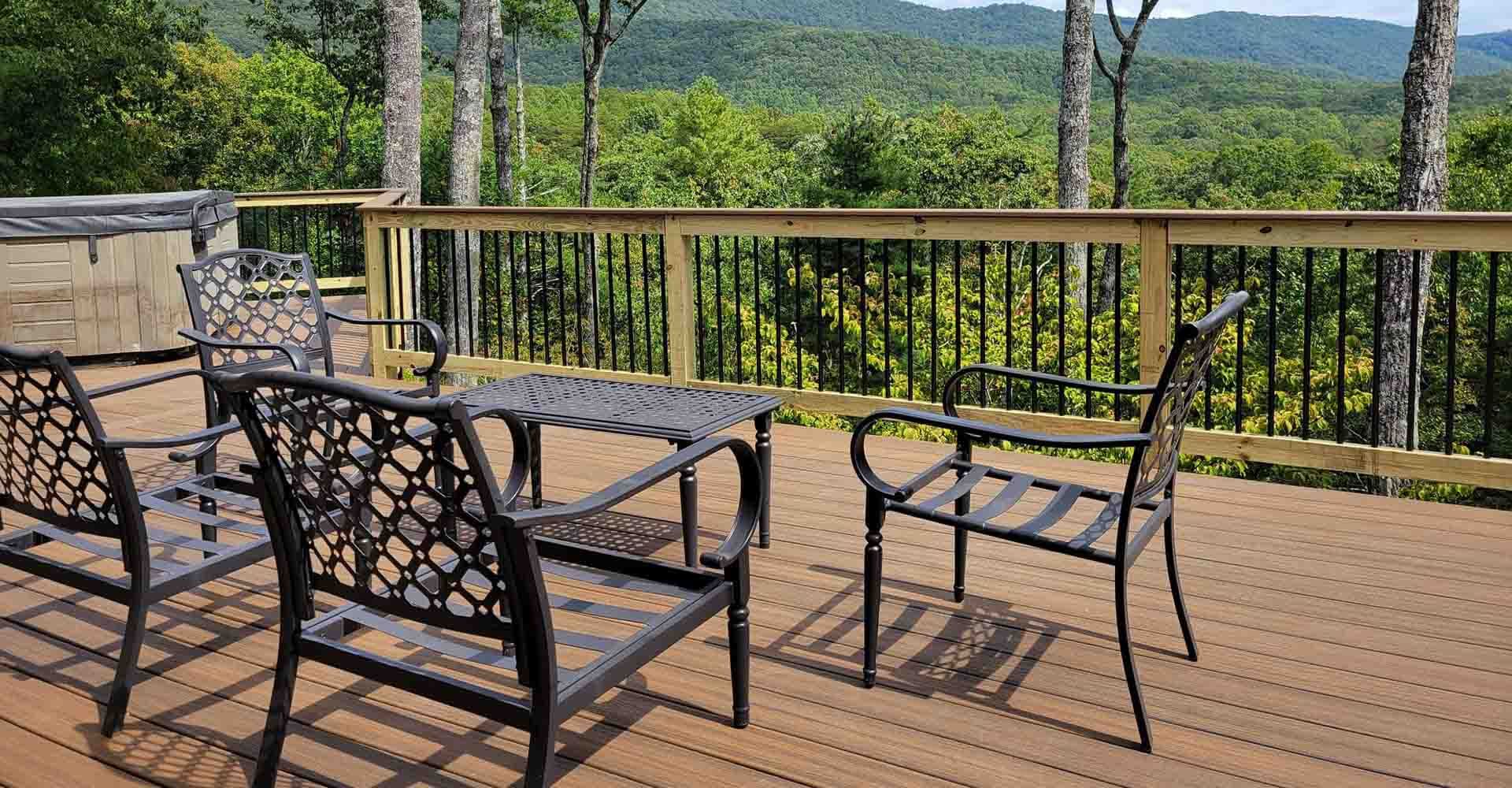 Deck with black metal furniture overlooking a mountain view and hot tub.