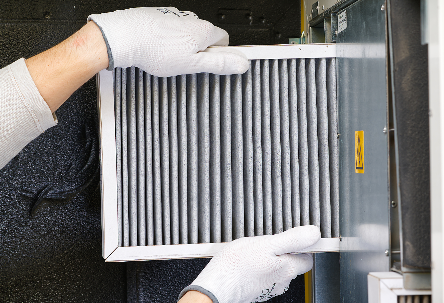A person wearing white gloves is holding a filter in their hands