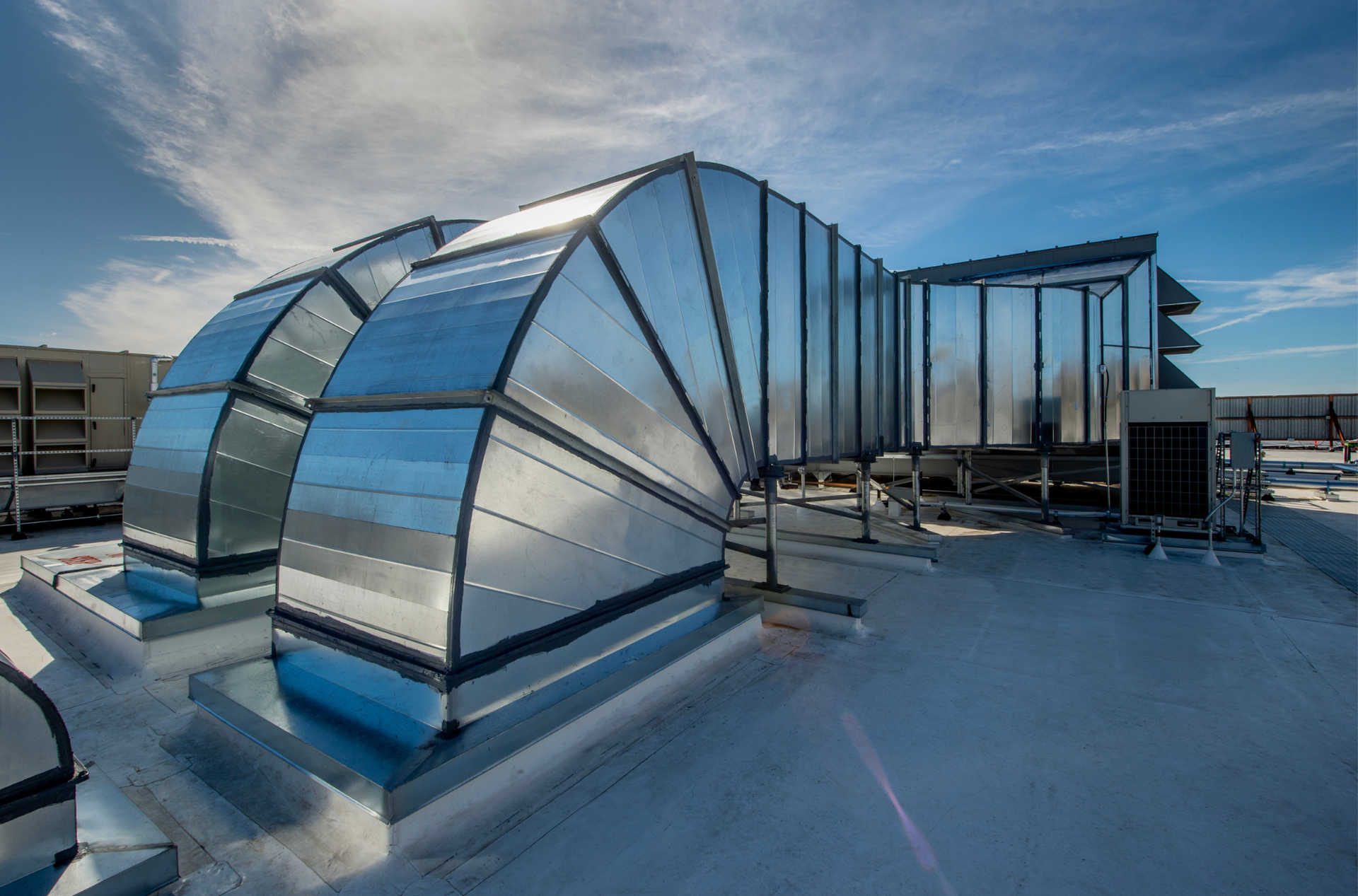 There are a lot of air conditioners on the roof of a building.