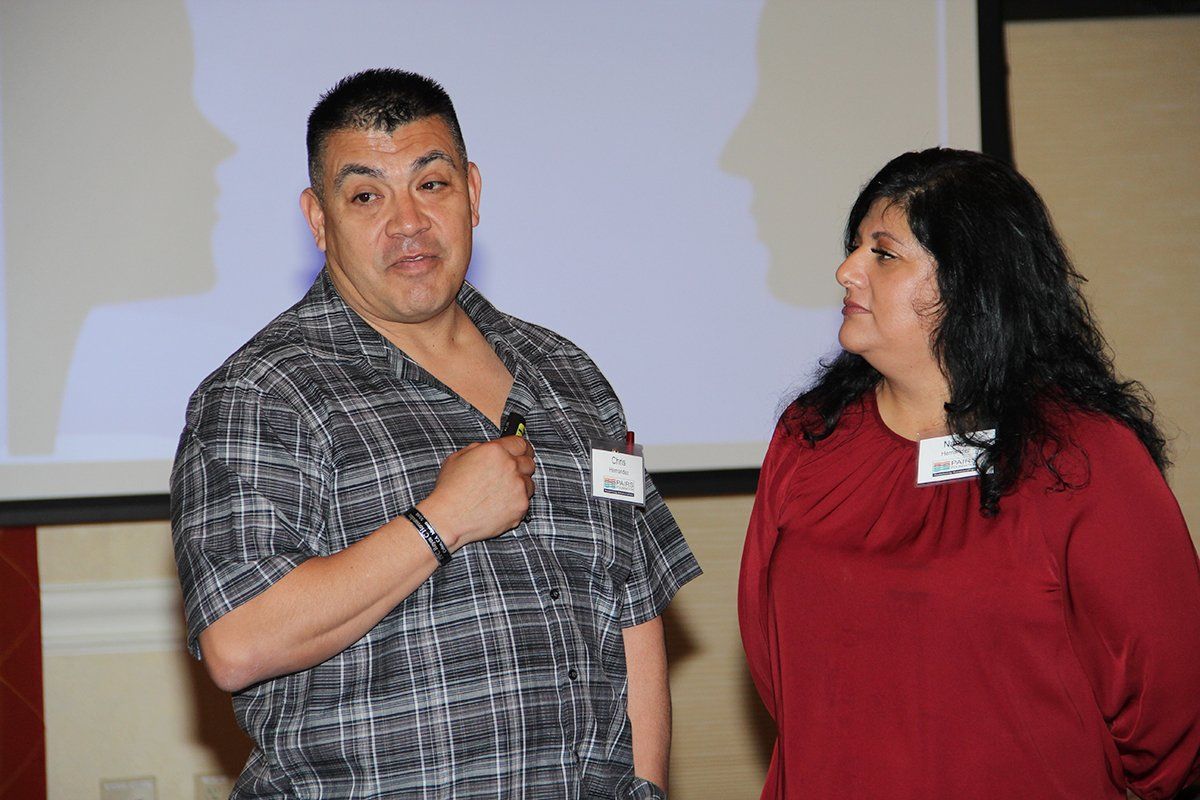 A man and a woman are standing next to each other in front of a projector screen.