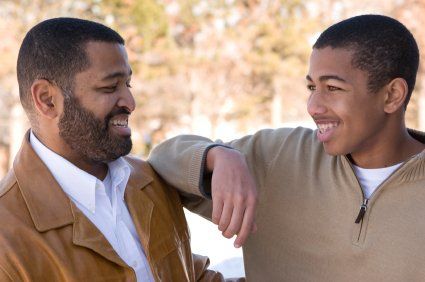 A man and a boy are standing next to each other and smiling.