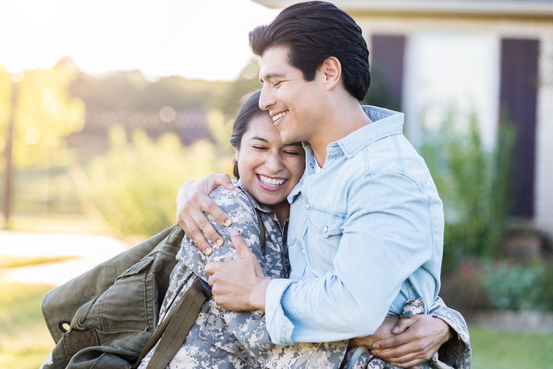 A man is hugging a woman in a military uniform.