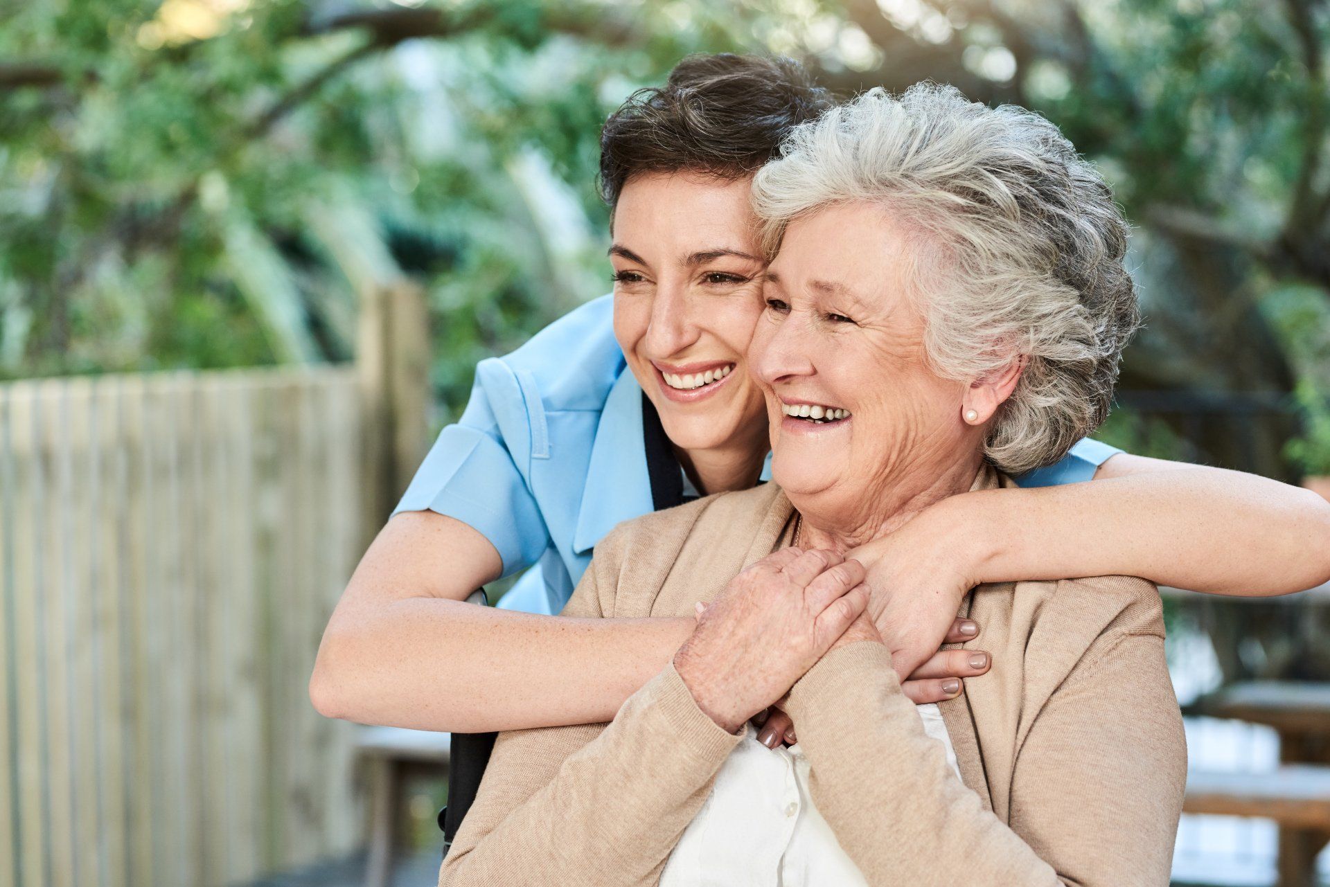 A young woman is hugging an older woman.