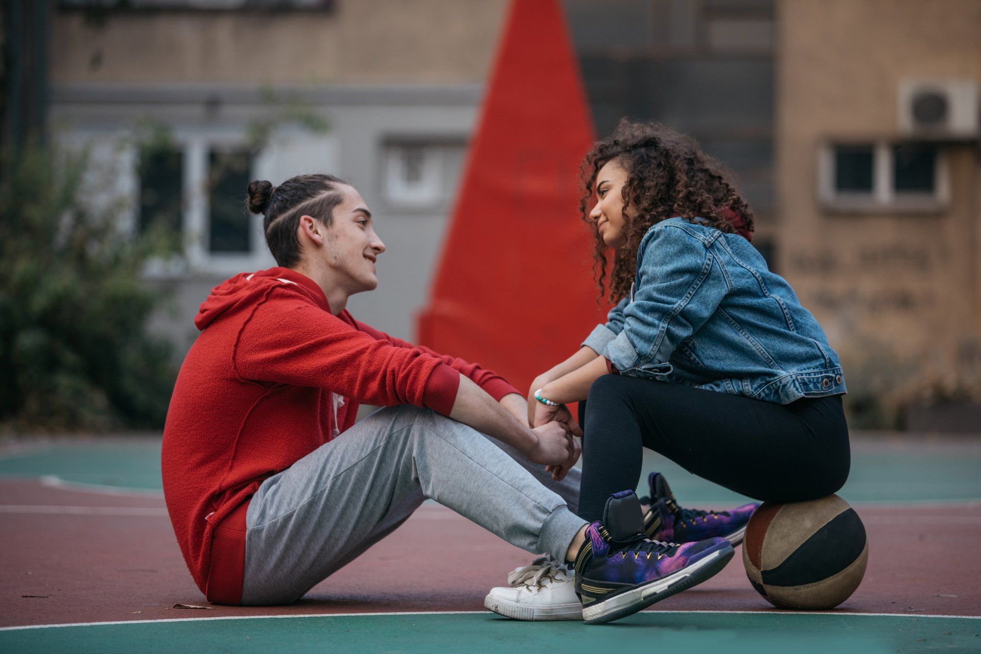 A man and a woman are sitting on a basketball court holding hands.