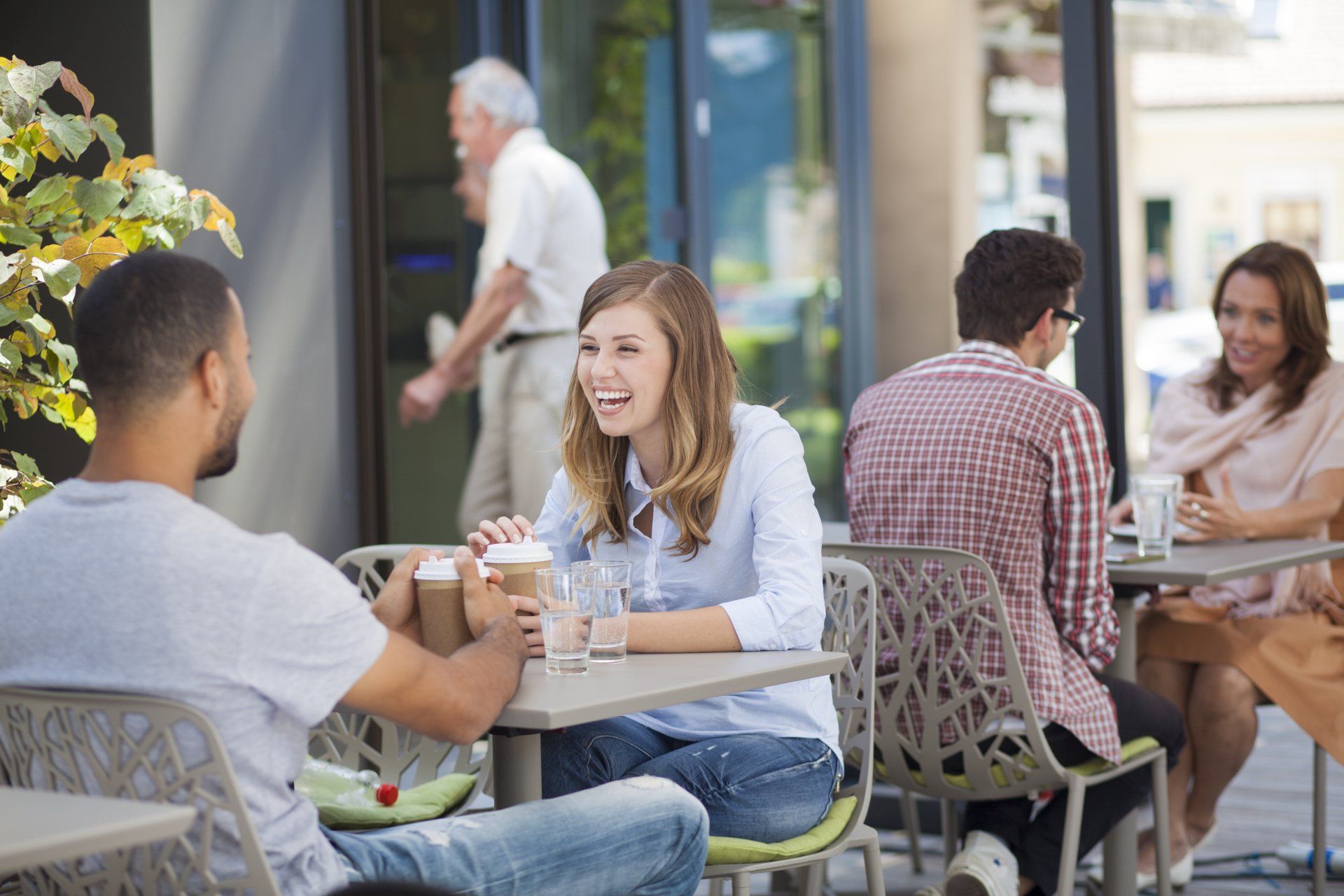 A group of people are sitting at tables outside of a restaurant.