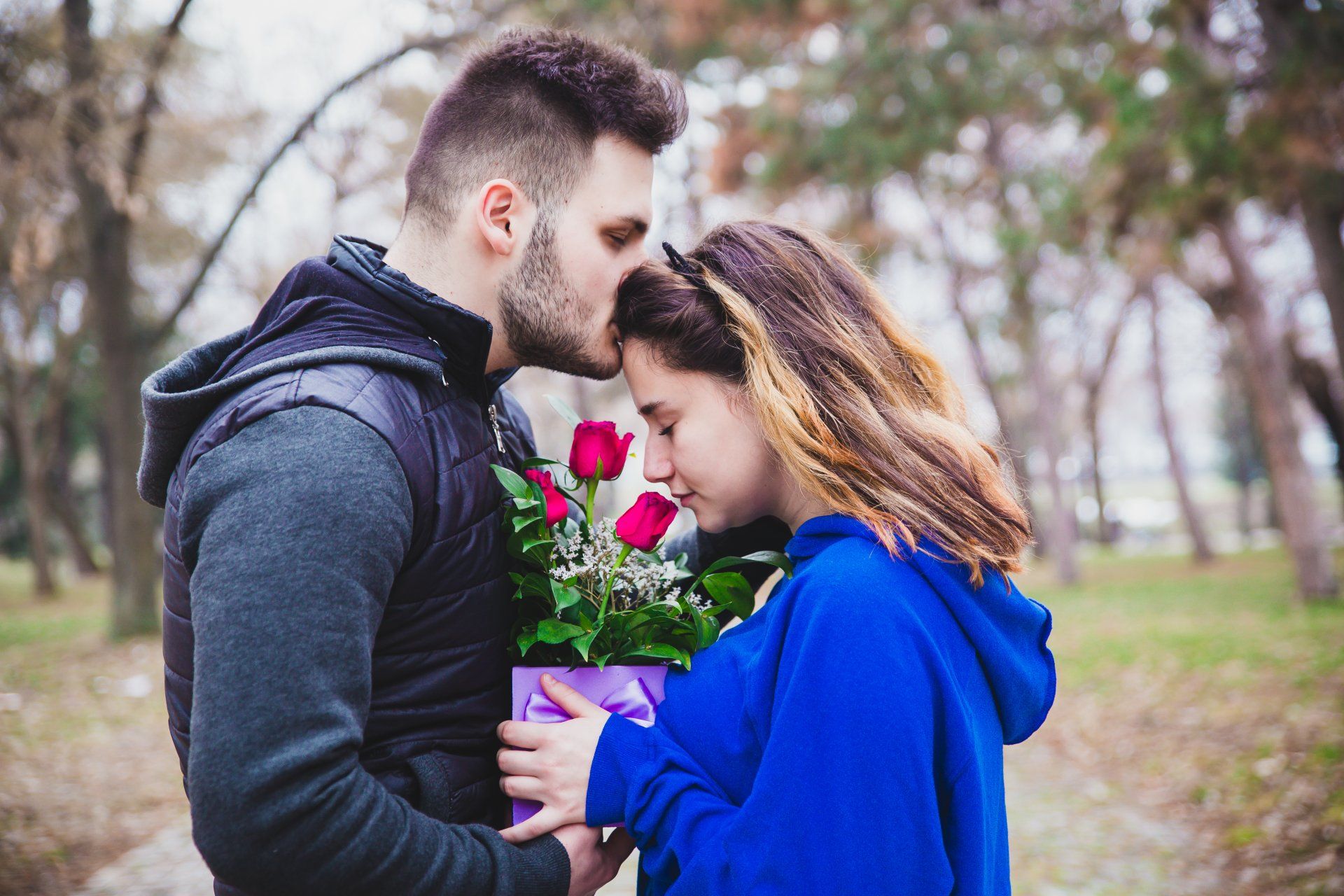 A man is giving a box of roses to a woman.